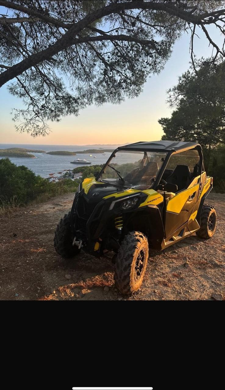 Yellow Can-Am buggy parked under a pine tree overlooking Hvar town and the Pakleni islands