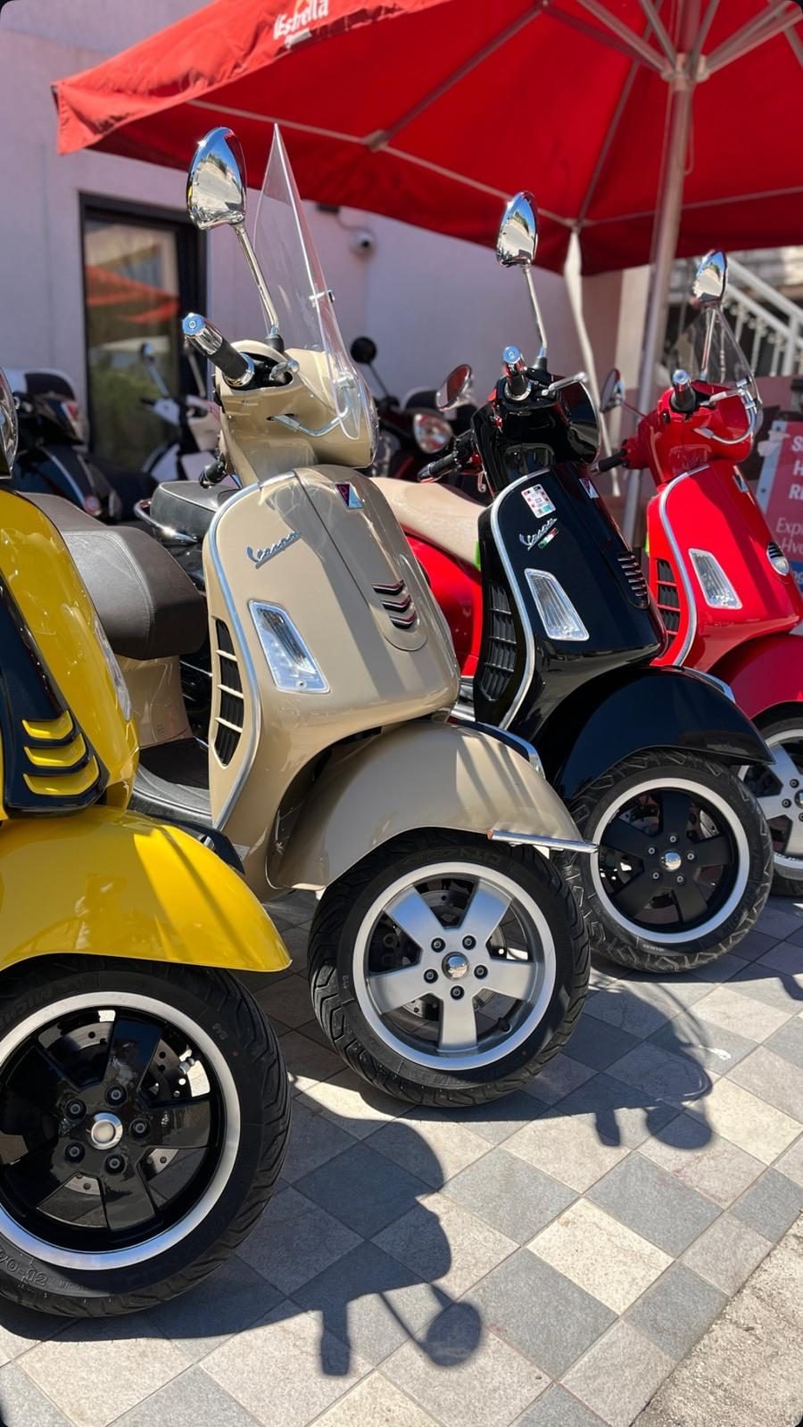 Vespa scooters in cream, black and red parked in a row